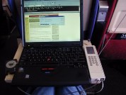 Laptop on airplane tray next to phone showing posting message