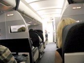 Back of seats and aisle in plane with very lit ceiling