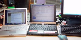 Three LCD screens and keyboards on a desk